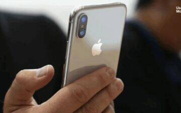 Person holding an Apple smartphone.